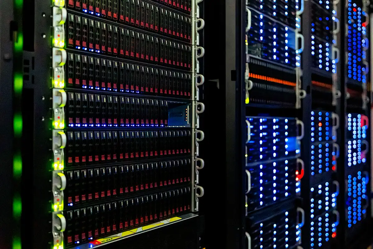 Server racks in a computer room, with rows of drive bays and blue and green status lights.
